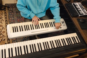 uma pessoa em pé ao lado de um teclado em uma mesa
