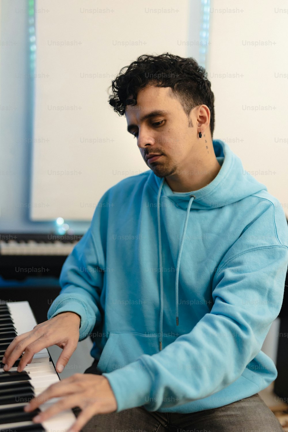 Ein Mann in einem blauen Kapuzenpulli, der Klavier spielt
