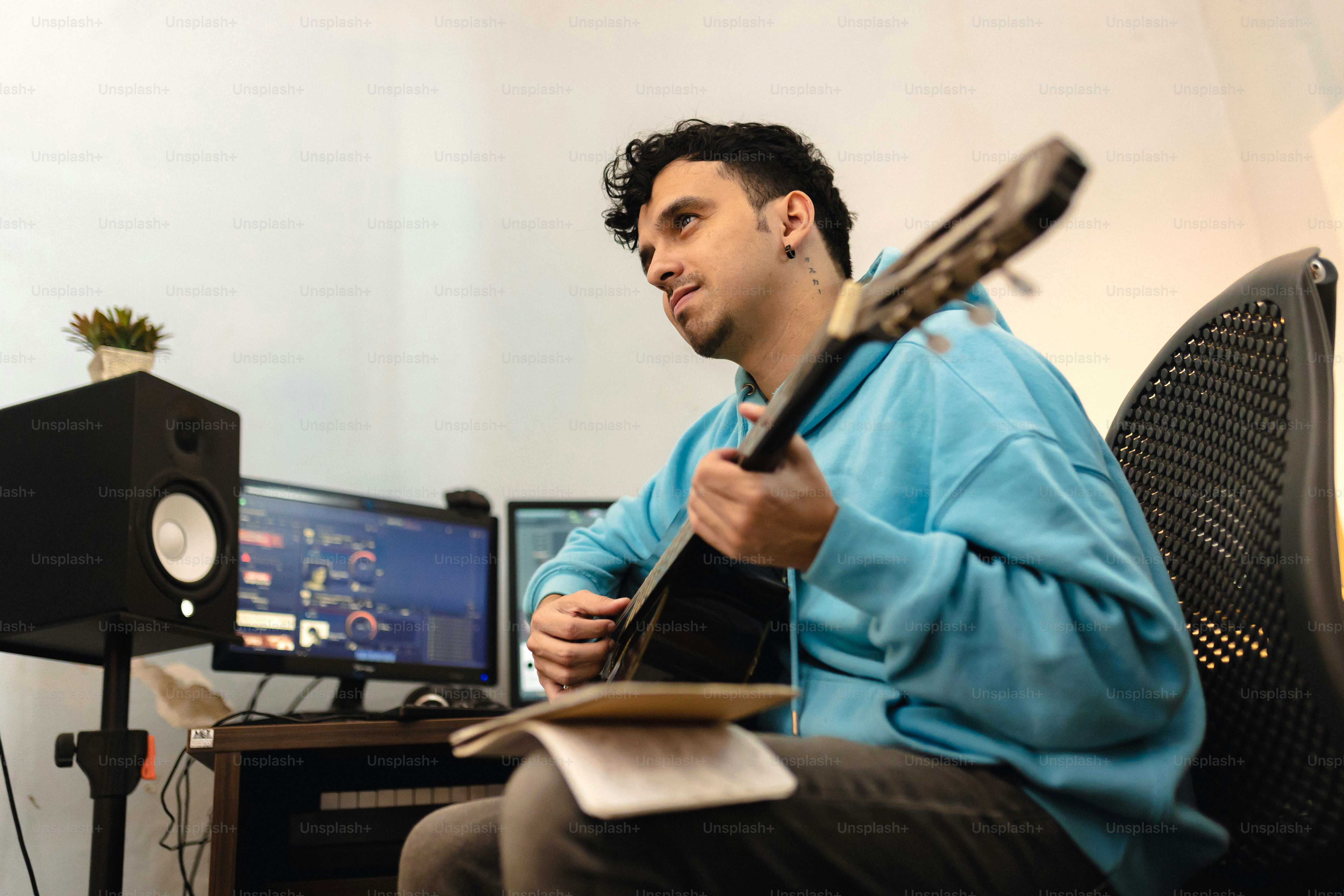A man sitting at his computer, playing his guitar, pondering, “what is indemnification?”