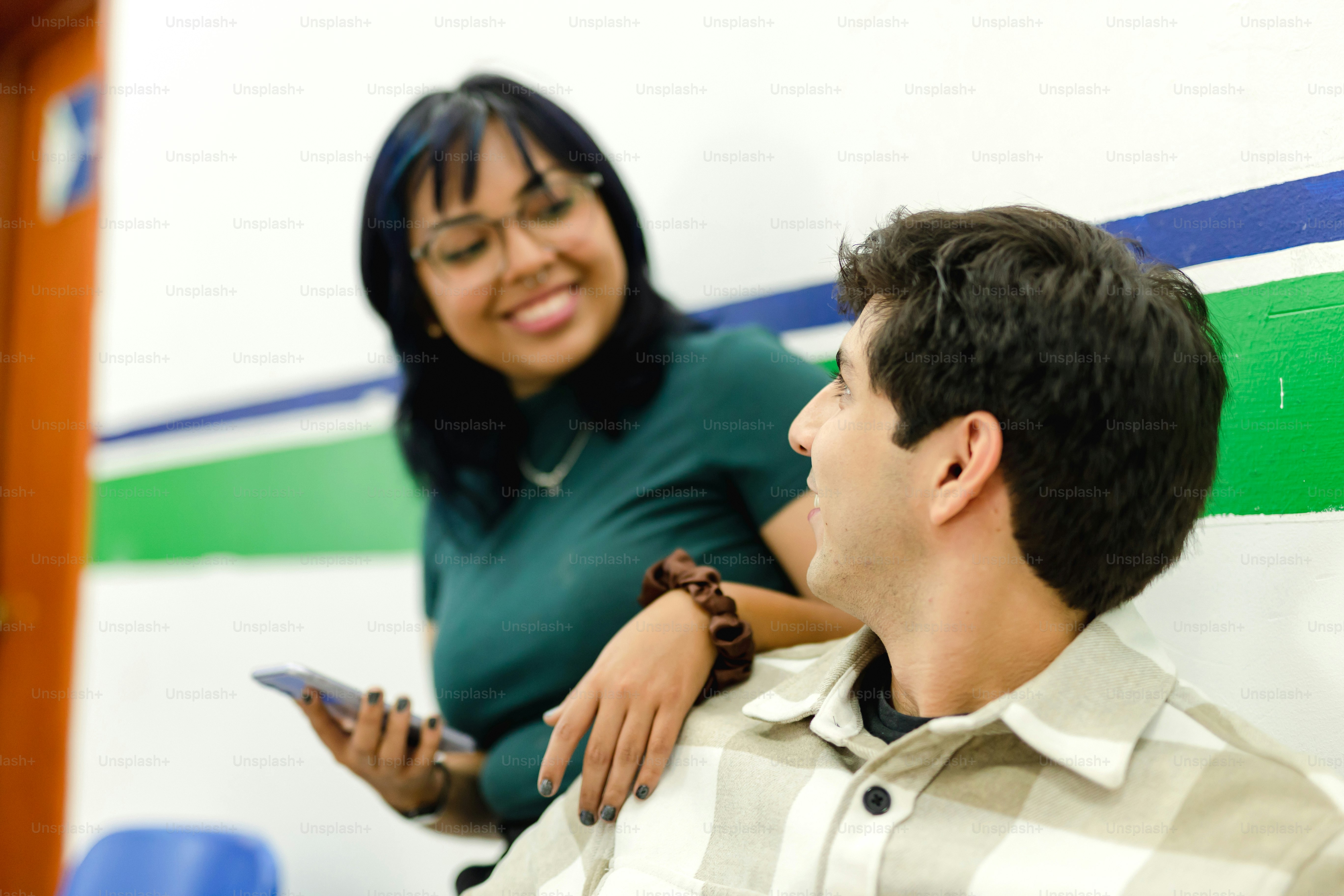 Ein Mann, der neben einer Frau auf einem Handy sitzt