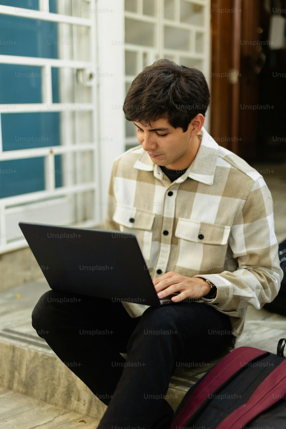 한 남자가 노트북 컴퓨터를 사용하여 계단에 앉아 있다