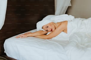 Una mujer acostada en una cama con sábanas blancas