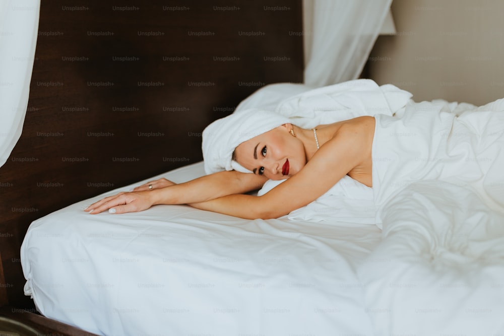 a woman laying on a bed with white sheets