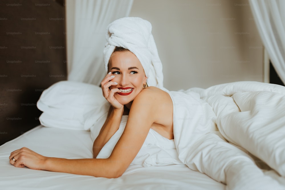 uma mulher deitada em uma cama com uma toalha na cabeça