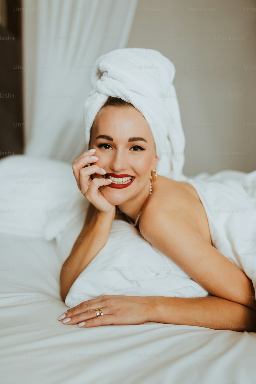 a woman laying on a bed with a towel on her head