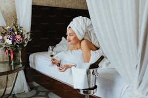 a woman sitting on a bed holding a glass of wine