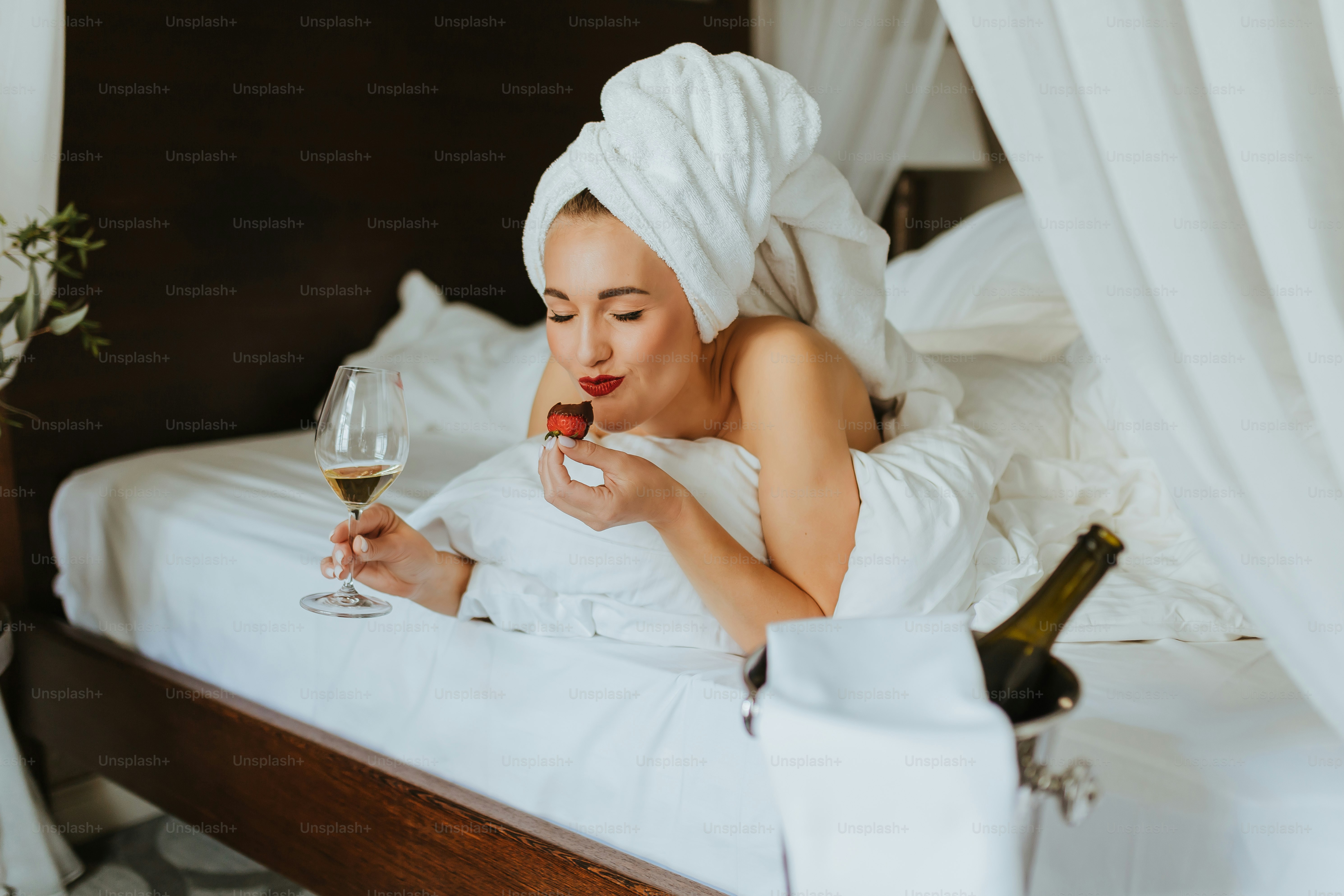 a woman laying in bed with a glass of wine