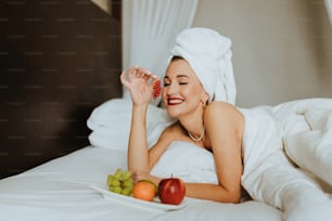 a woman laying in bed with a plate of fruit