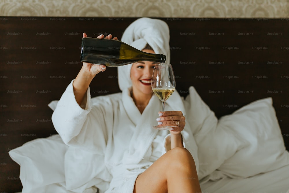 a woman sitting on a bed holding a glass of wine