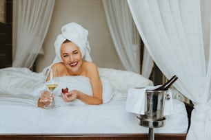 a woman laying in bed with a glass of wine