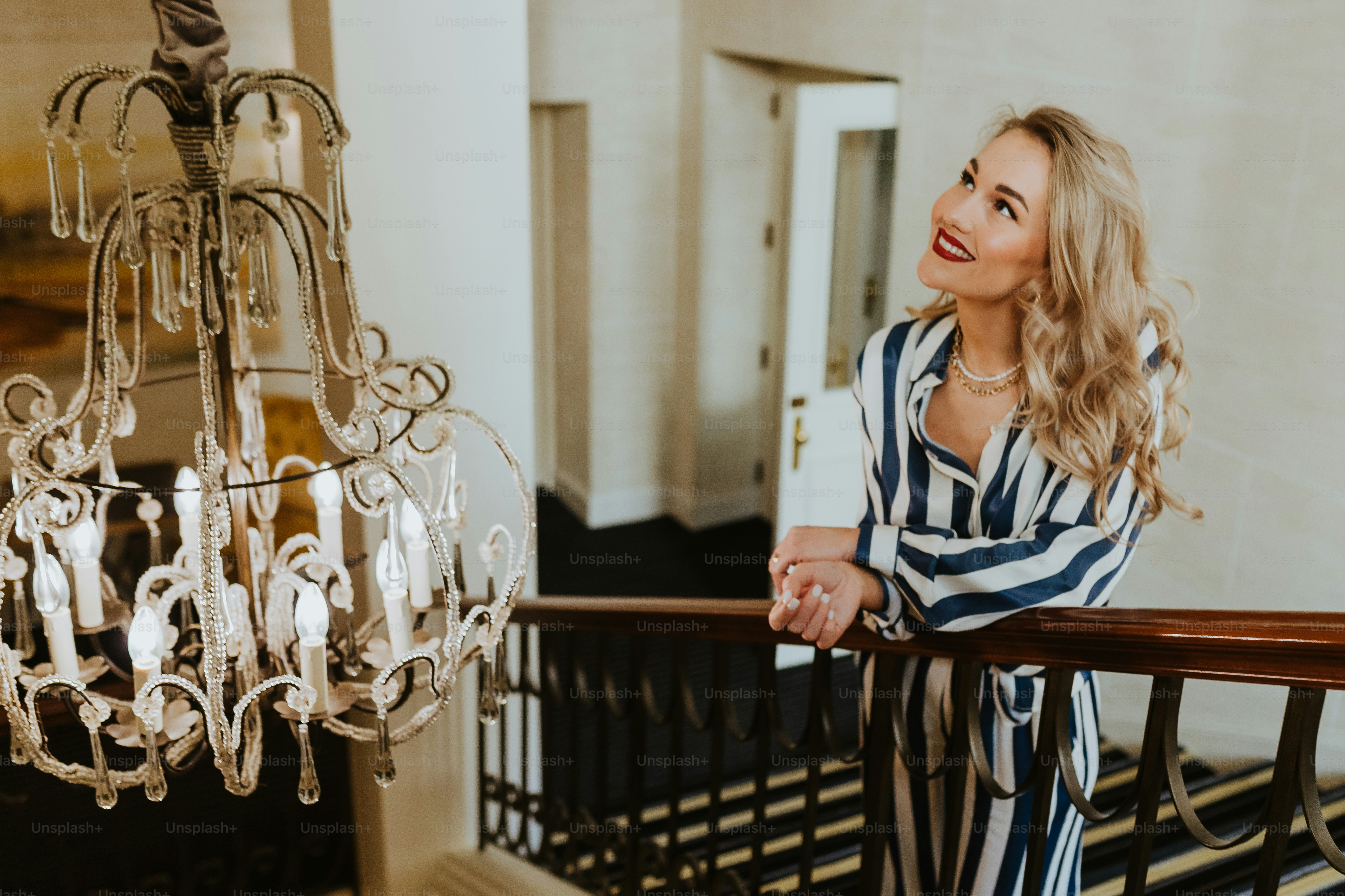 a woman standing on a balcony next to a chandelier