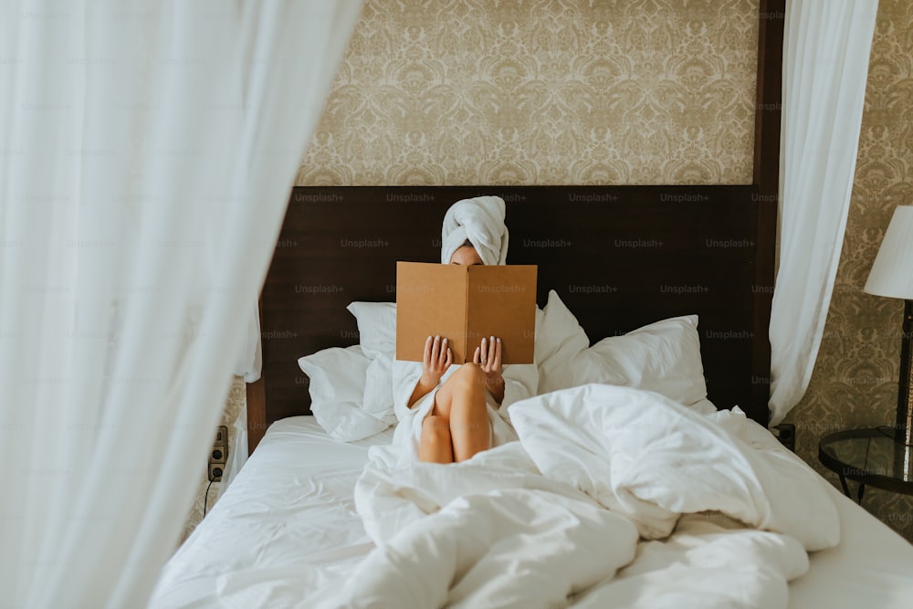 a woman laying in bed with a box on her head