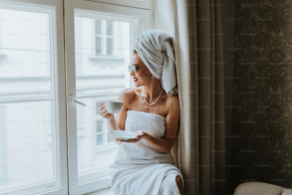 a woman sitting on a window sill holding a cup of coffee