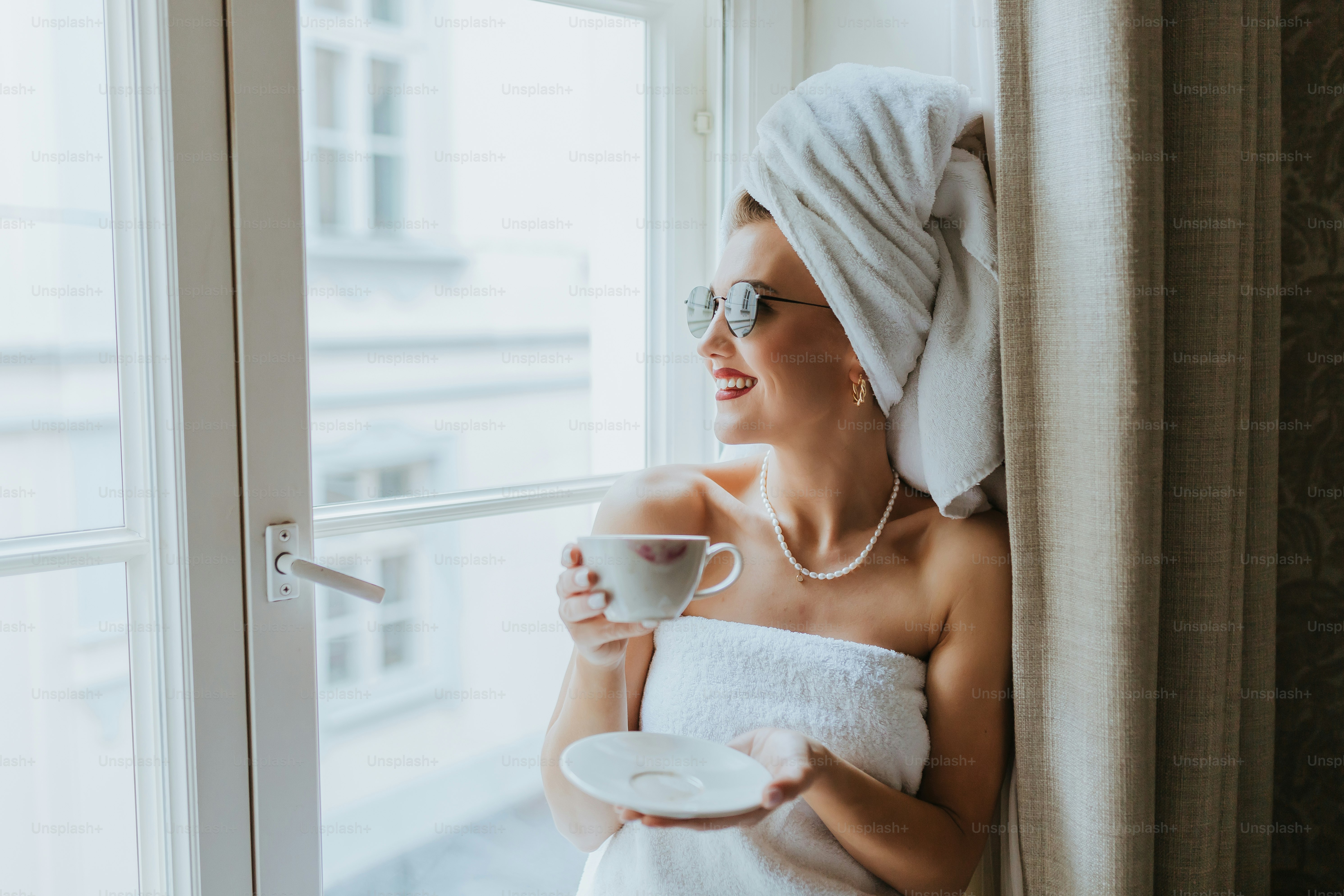 una donna in un asciugamano che tiene una tazza e un piattino