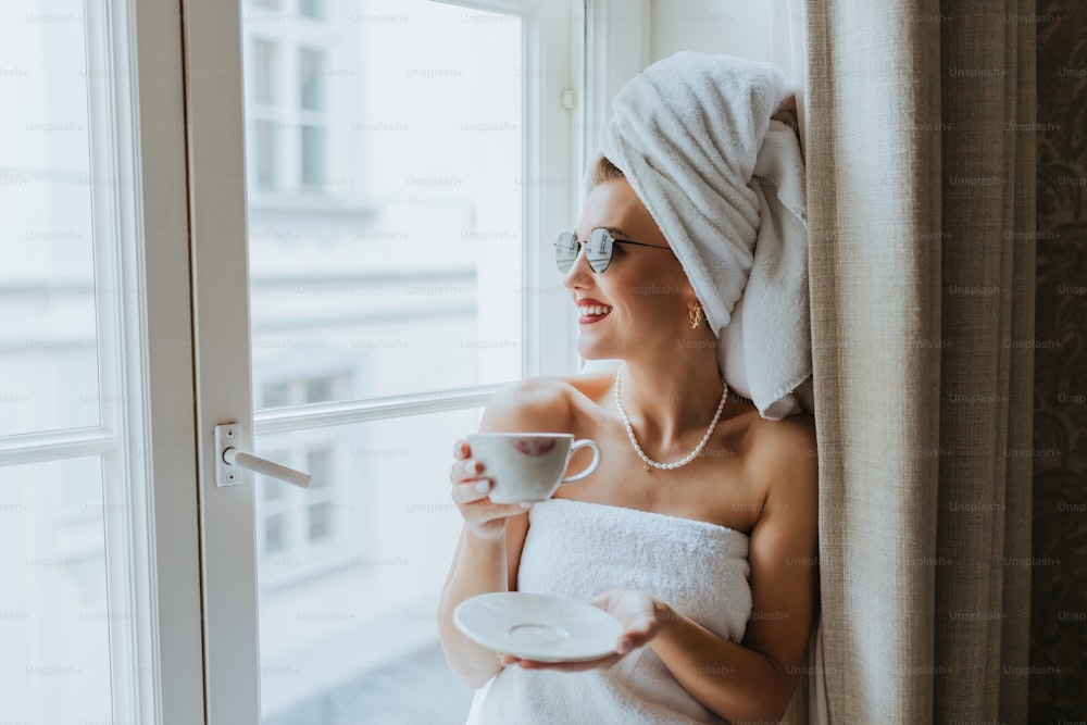 a woman in a towel holding a cup and saucer