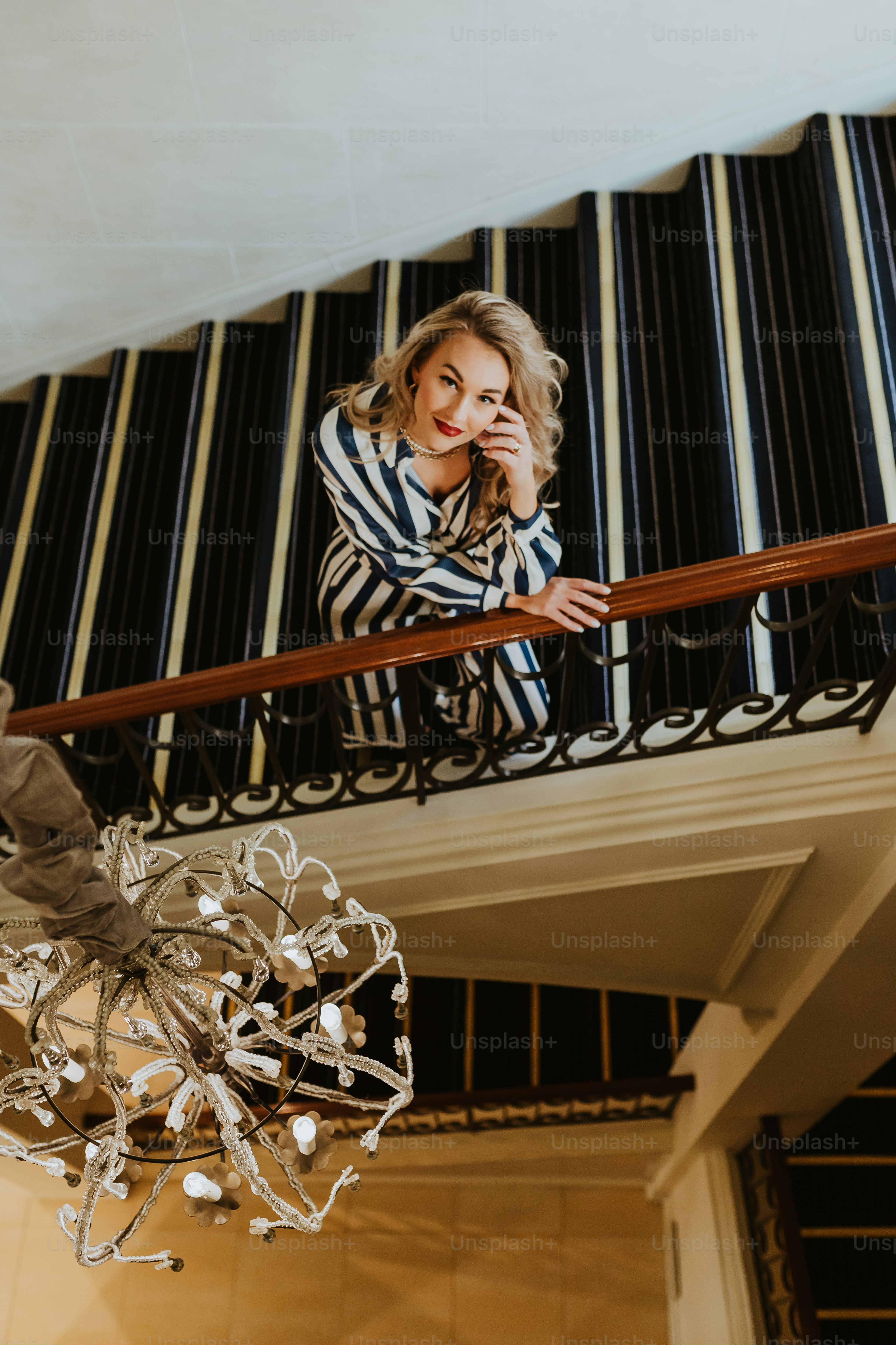 a woman standing on a balcony with a chandelier