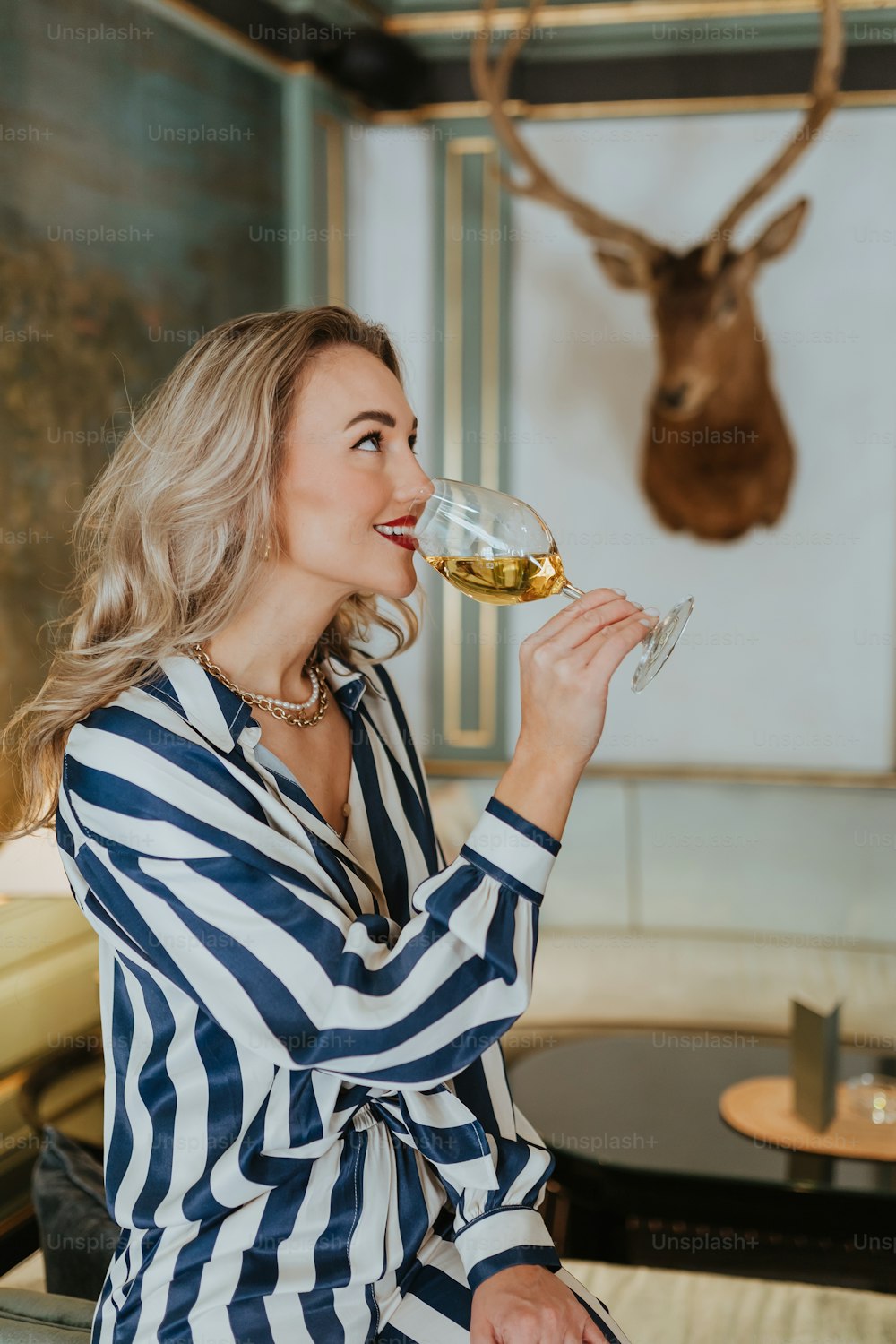 a woman sitting on a couch drinking a glass of wine