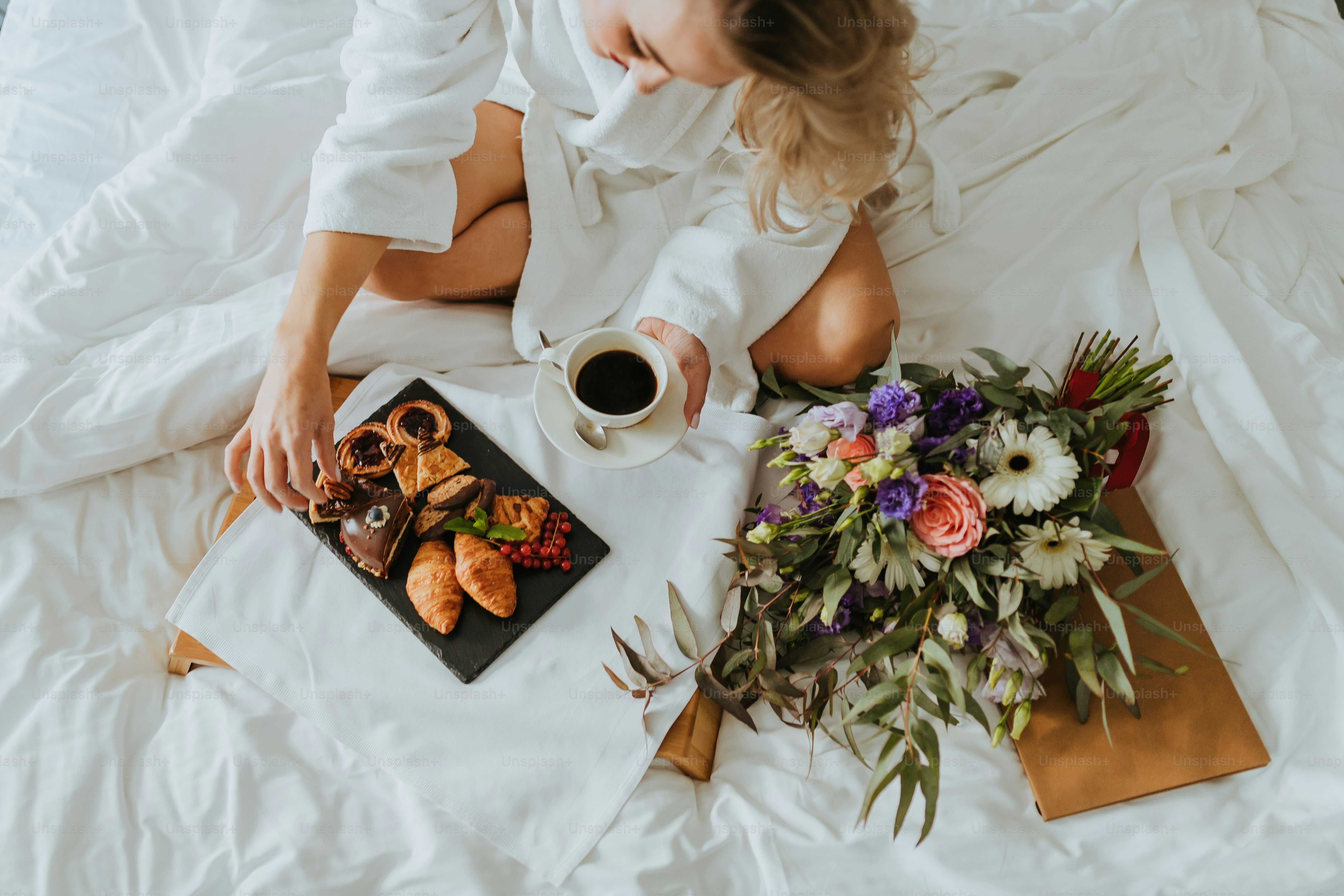 a woman sitting on a bed next to a tray of food