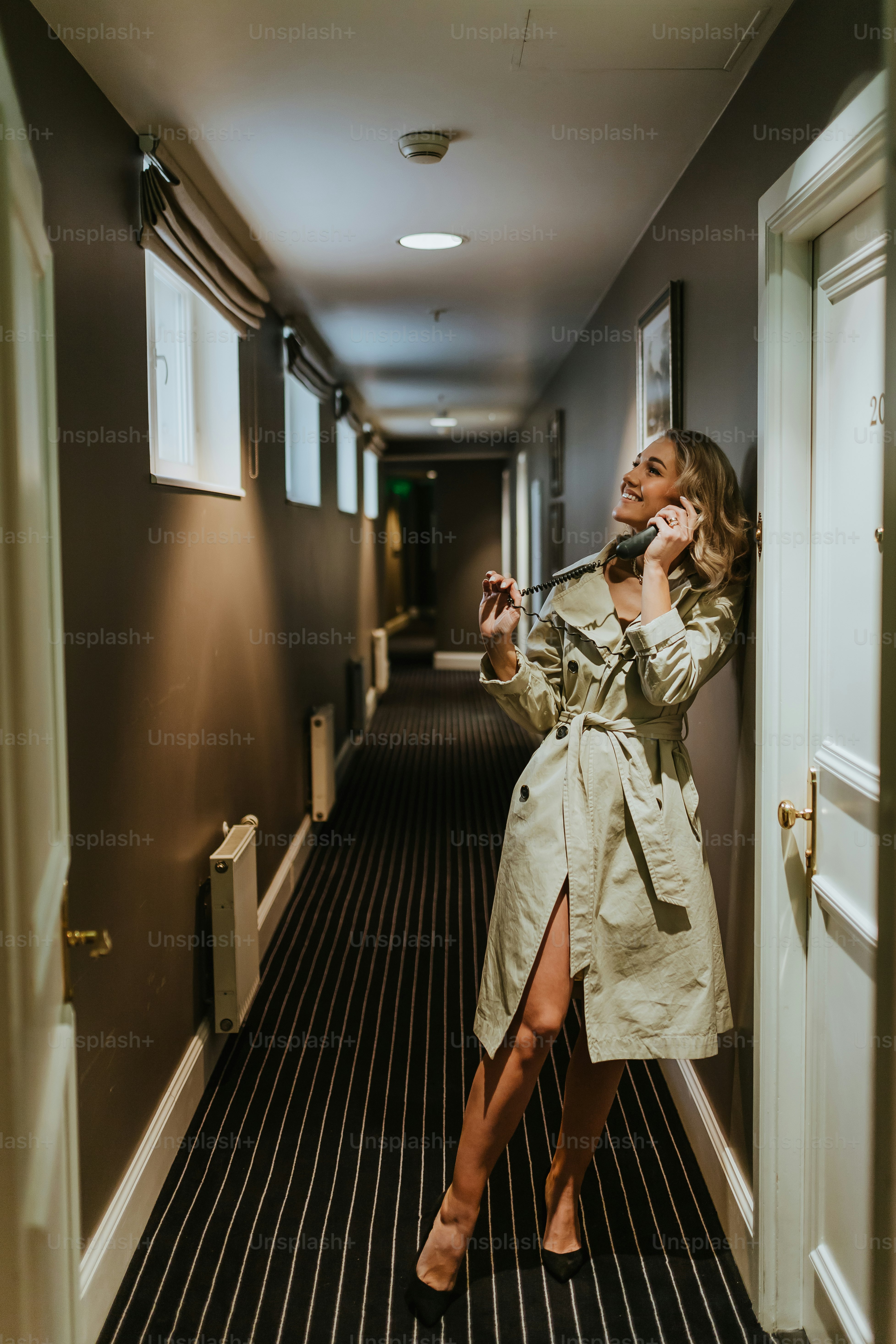 a woman in a trench coat talking on a cell phone