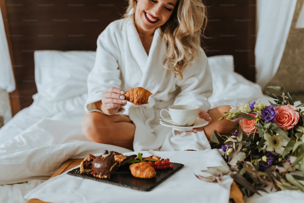 Une femme assise sur un lit tenant une tasse de café
