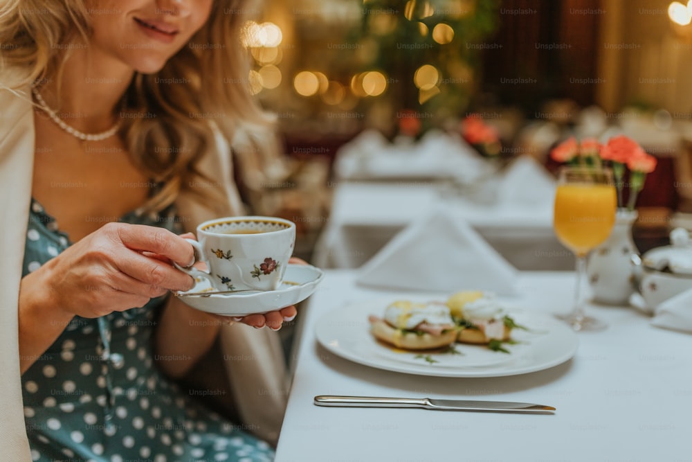 Eine Frau, die an einem Tisch mit einem Teller mit Essen und einer Tasse Kaffee sitzt