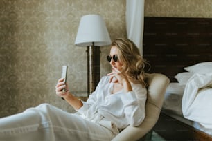 a woman sitting in a chair holding a cell phone