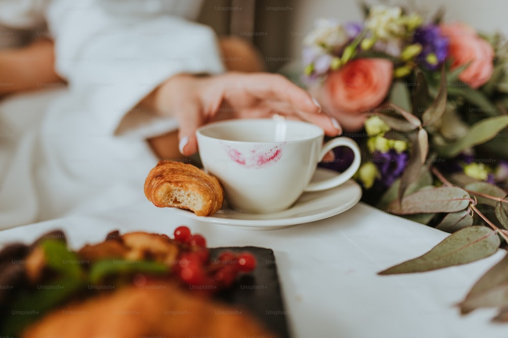 a person holding a cup and saucer on a table