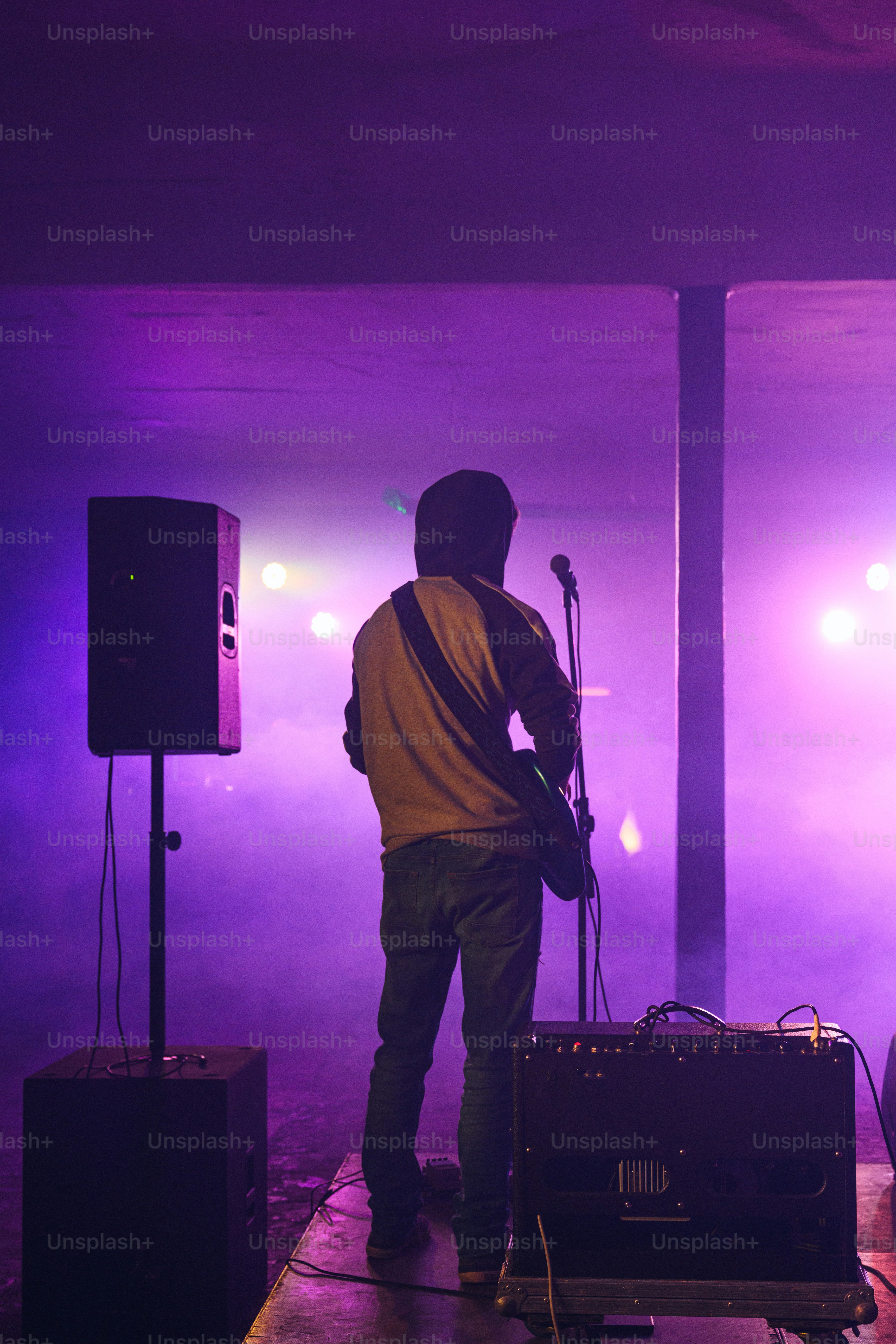a man standing in front of a stage with a guitar
