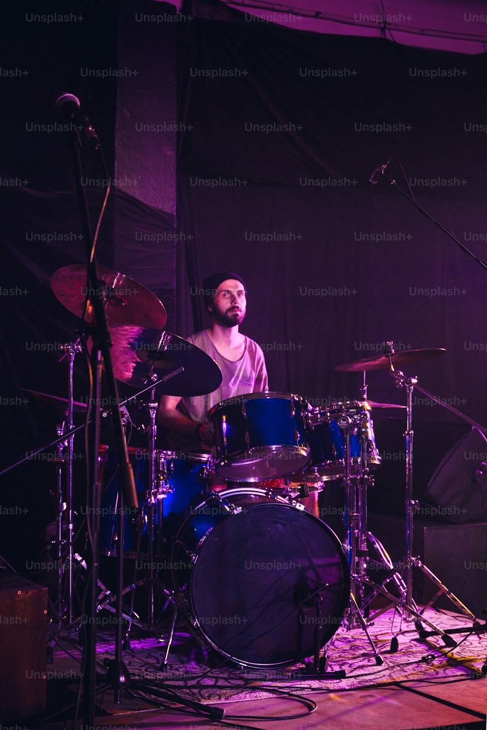 um homem com barba tocando bateria no palco