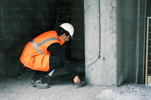 a man in an orange safety vest is fixing a wall