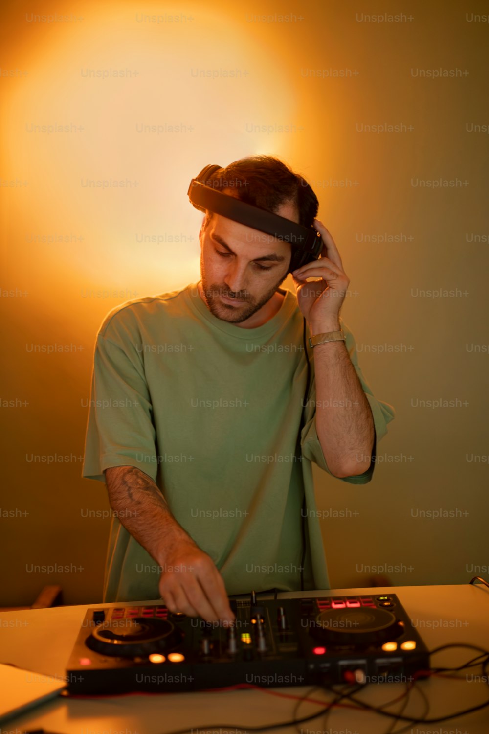 Un hombre con camisa verde está usando el tocadiscos de un DJ