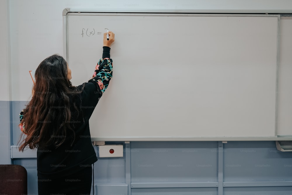 a woman is writing on a white board