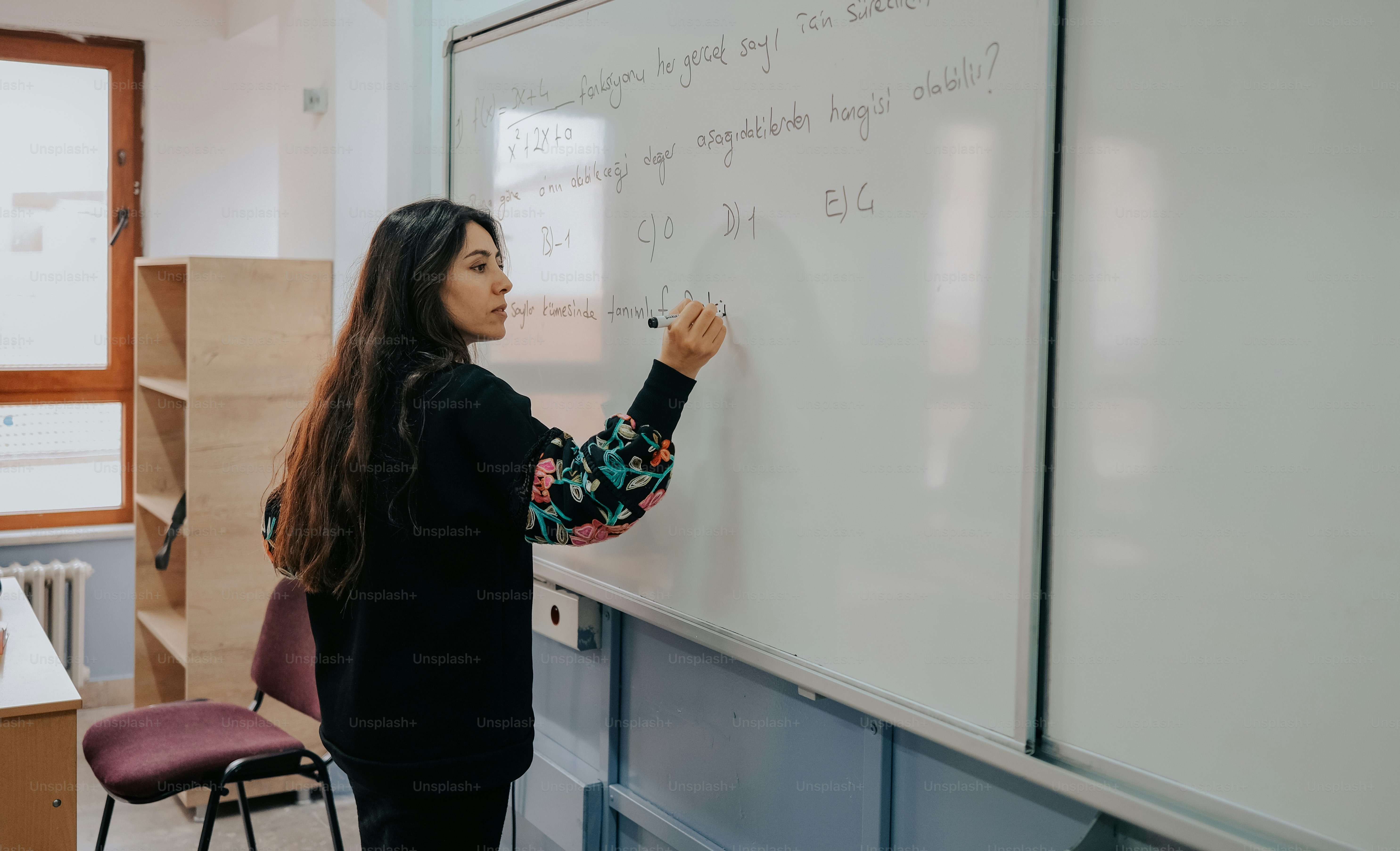 A woman writing on a whiteboard in a classroom photo classroom image