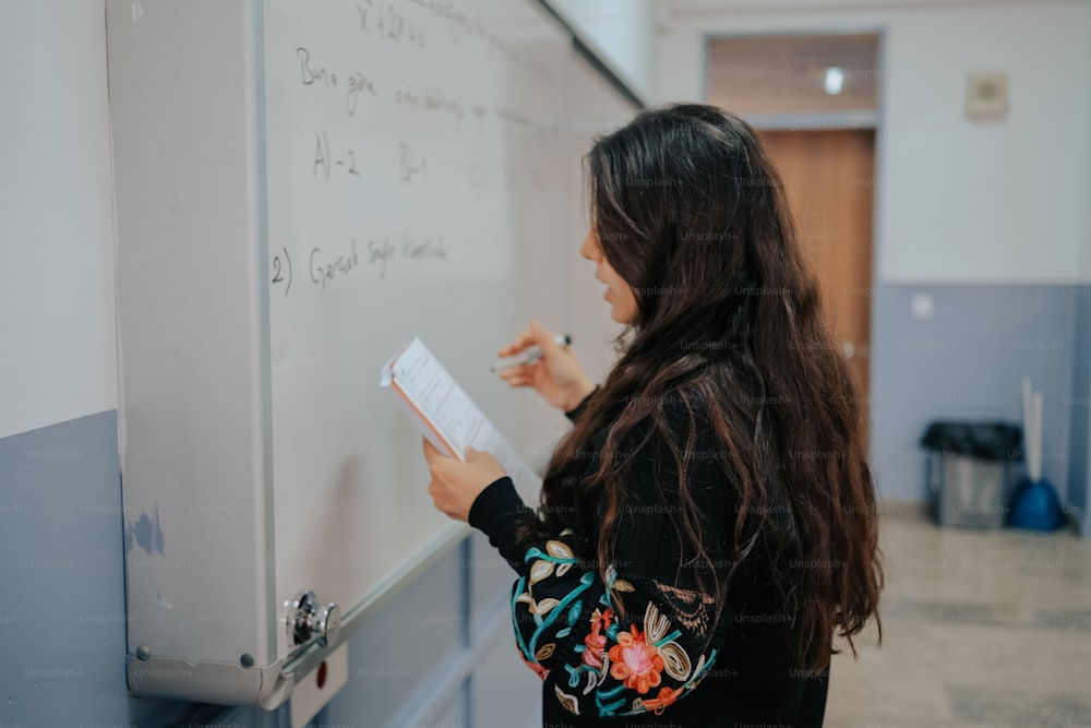 a woman writing on a whiteboard in a room