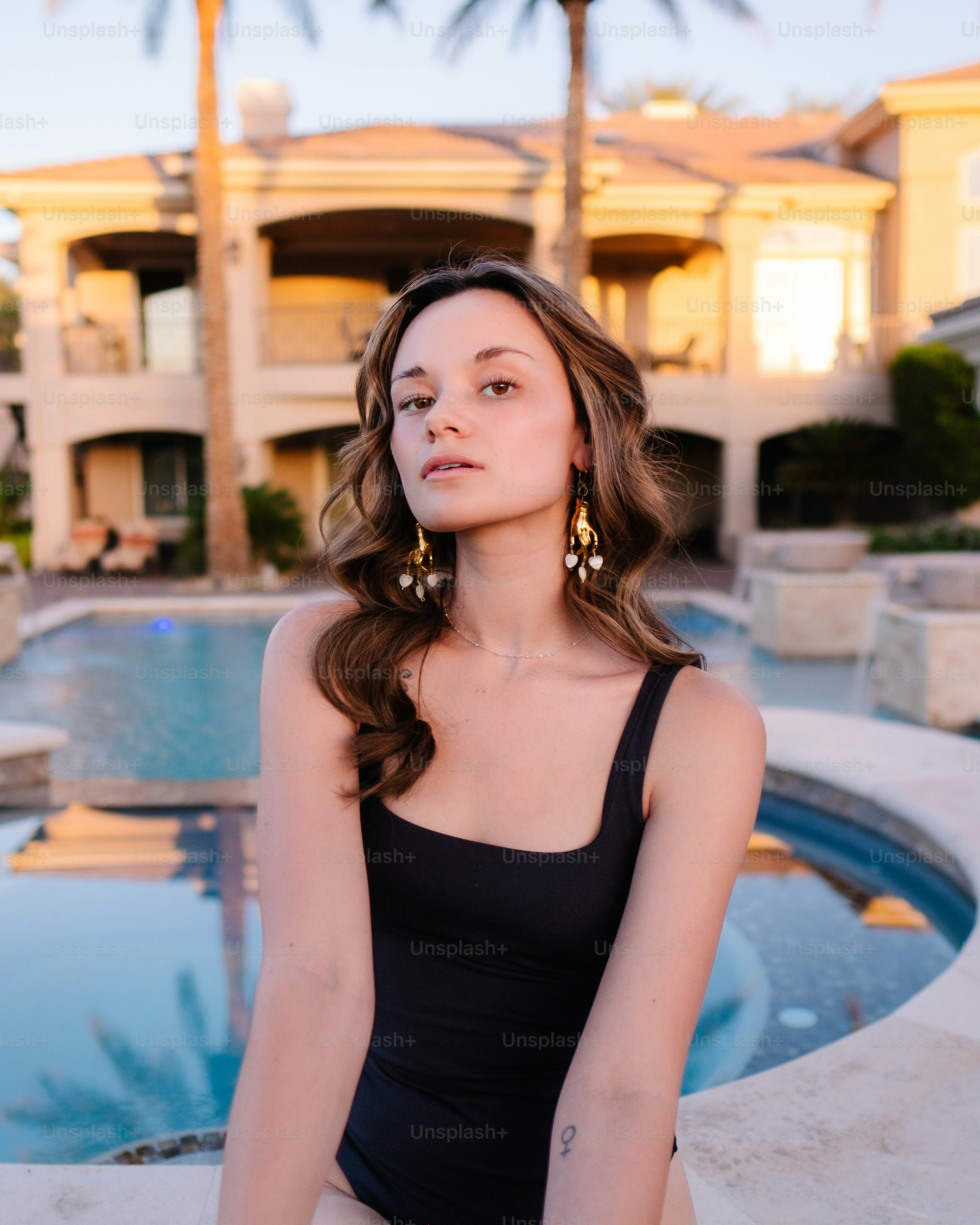 a woman sitting on a ledge next to a pool