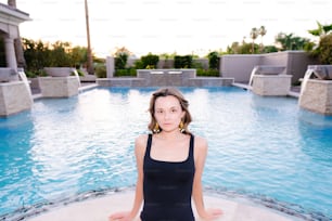 a woman in a black tank top sitting in a pool
