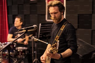 Un homme jouant de la guitare devant un micro