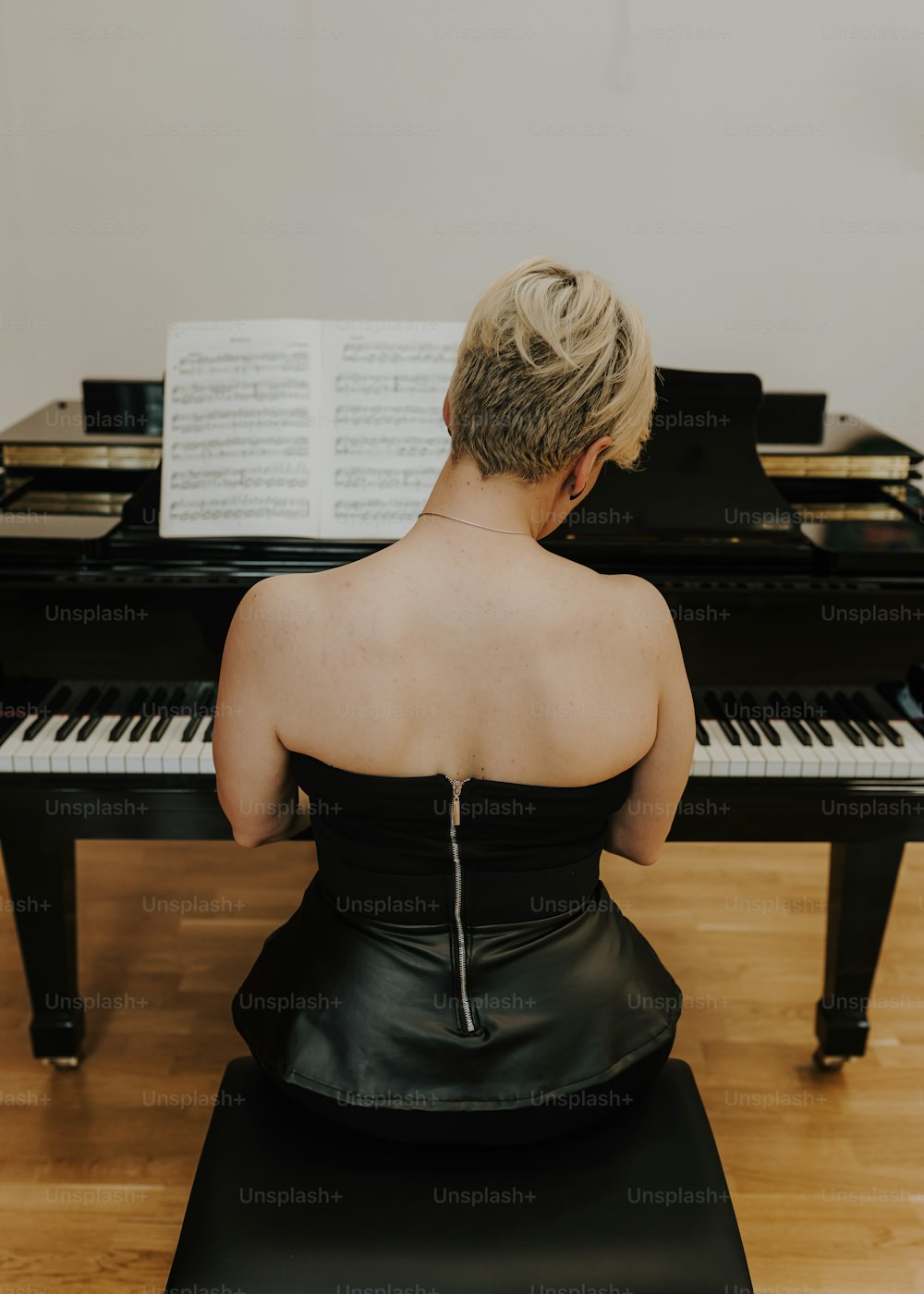 검은 드레스를 입은 여자가 피아노 앞에 앉아 있다