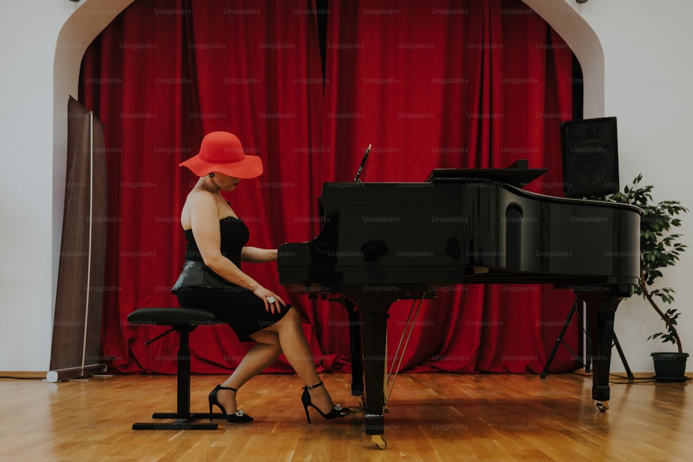 a woman sitting at a piano in front of a red curtain