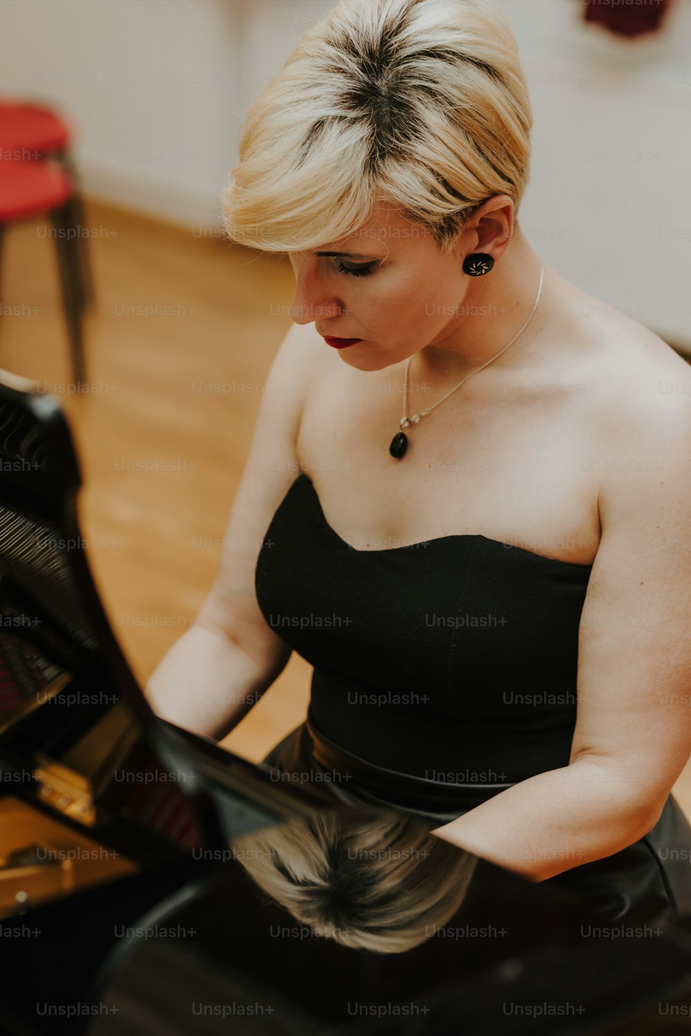 a woman in a black dress playing a piano
