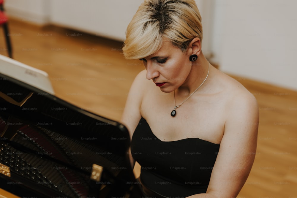 Una mujer con un vestido negro tocando un piano