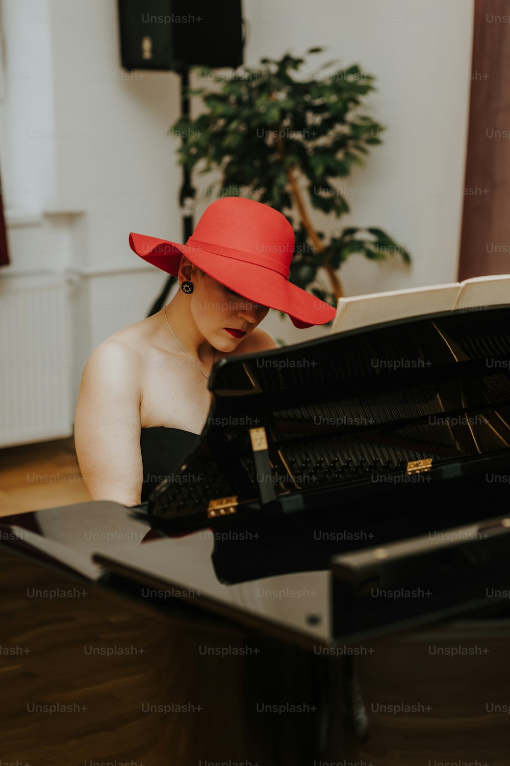 uma mulher usando um chapéu vermelho sentada em um piano