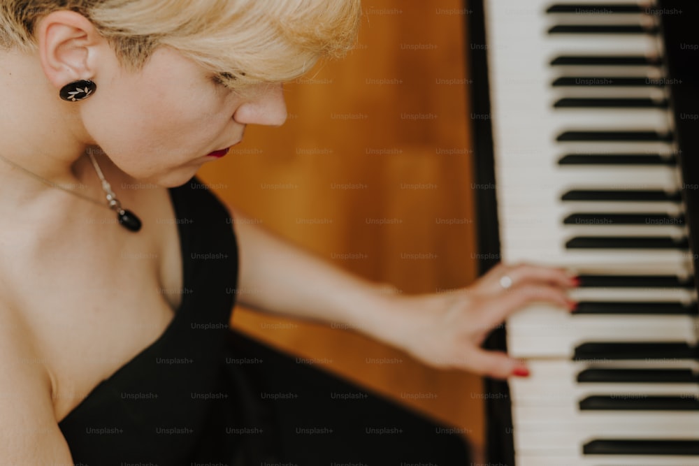 a woman in a black dress playing a piano