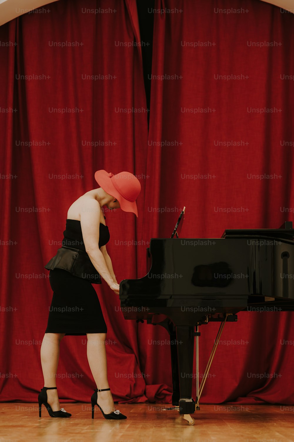 uma mulher em um vestido preto está tocando um piano