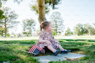 a little girl sitting on the ground in the grass