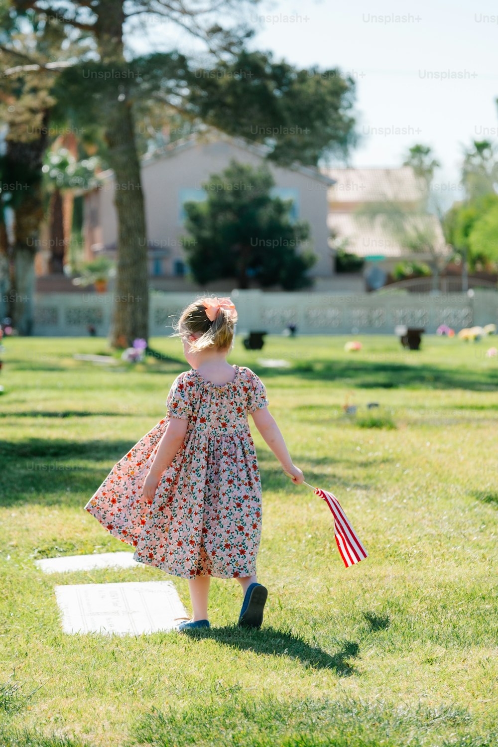 a little girl in a dress holding an american flag