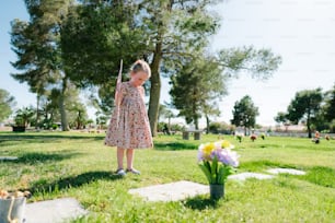 a little girl standing in the grass holding a baseball bat