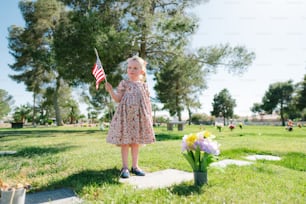 a little girl holding an american flag in a park