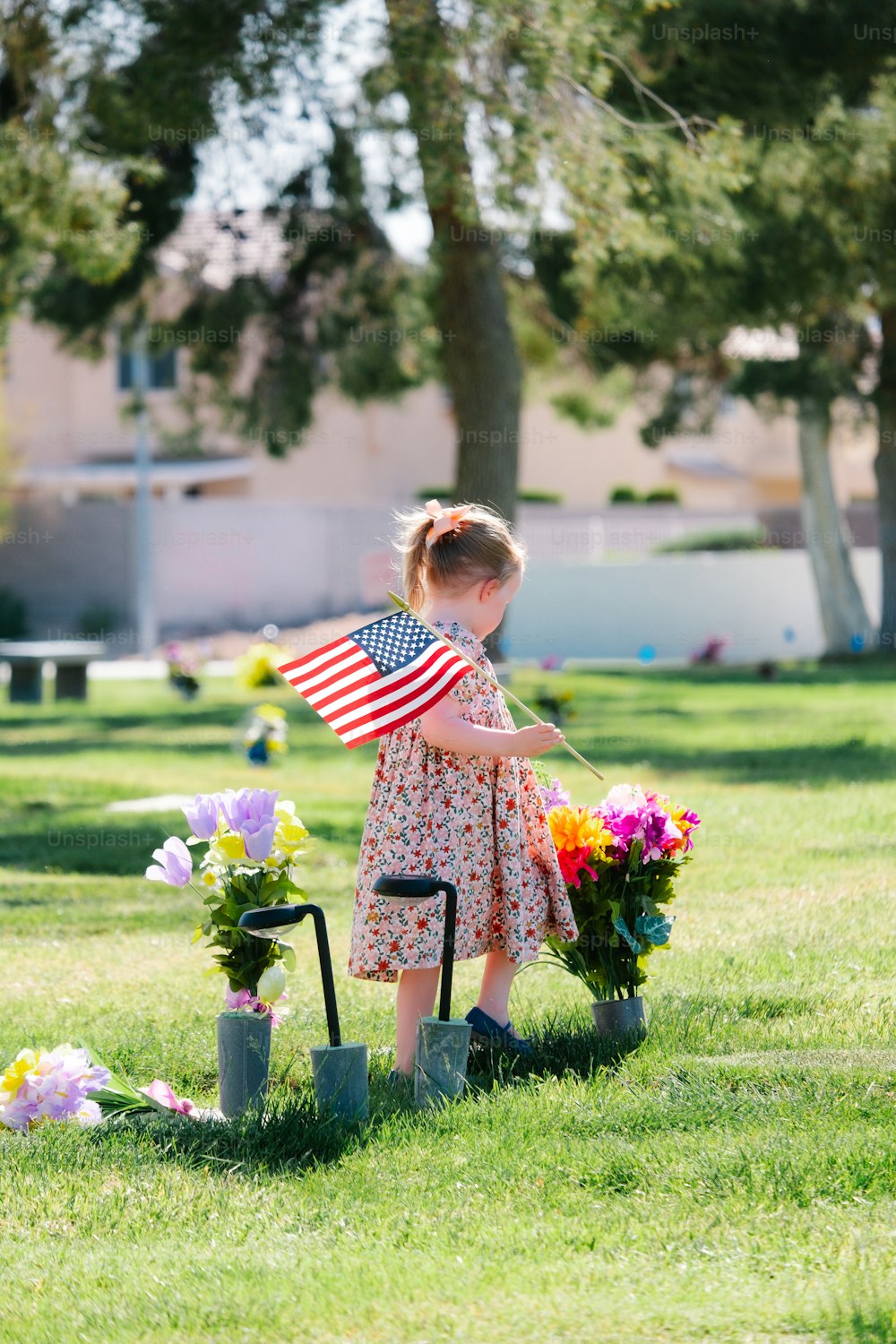 a little girl holding an american flag in a field