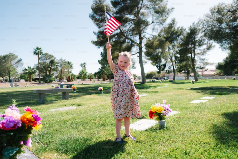 Uma menina segurando uma bandeira americana em um cemitério